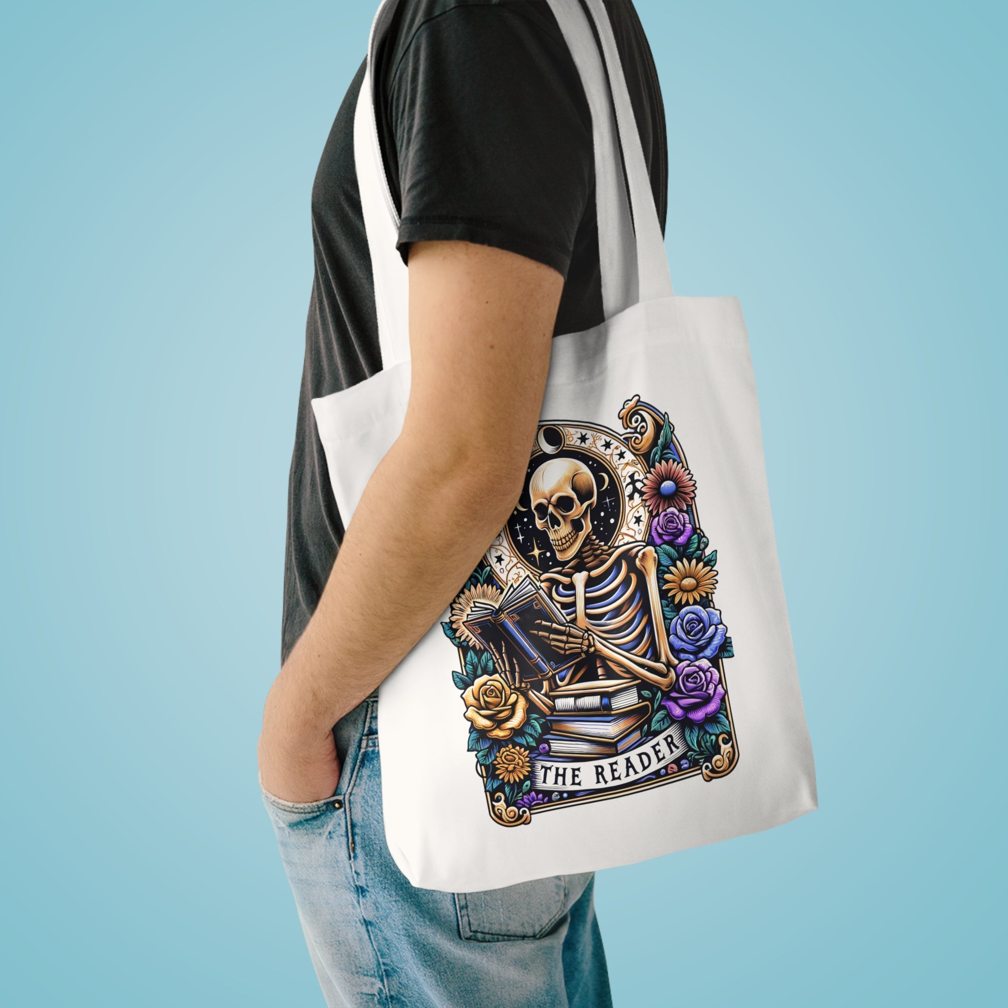 Person holding a tote bag with a skeleton design and 'The Reader' text on a blue background