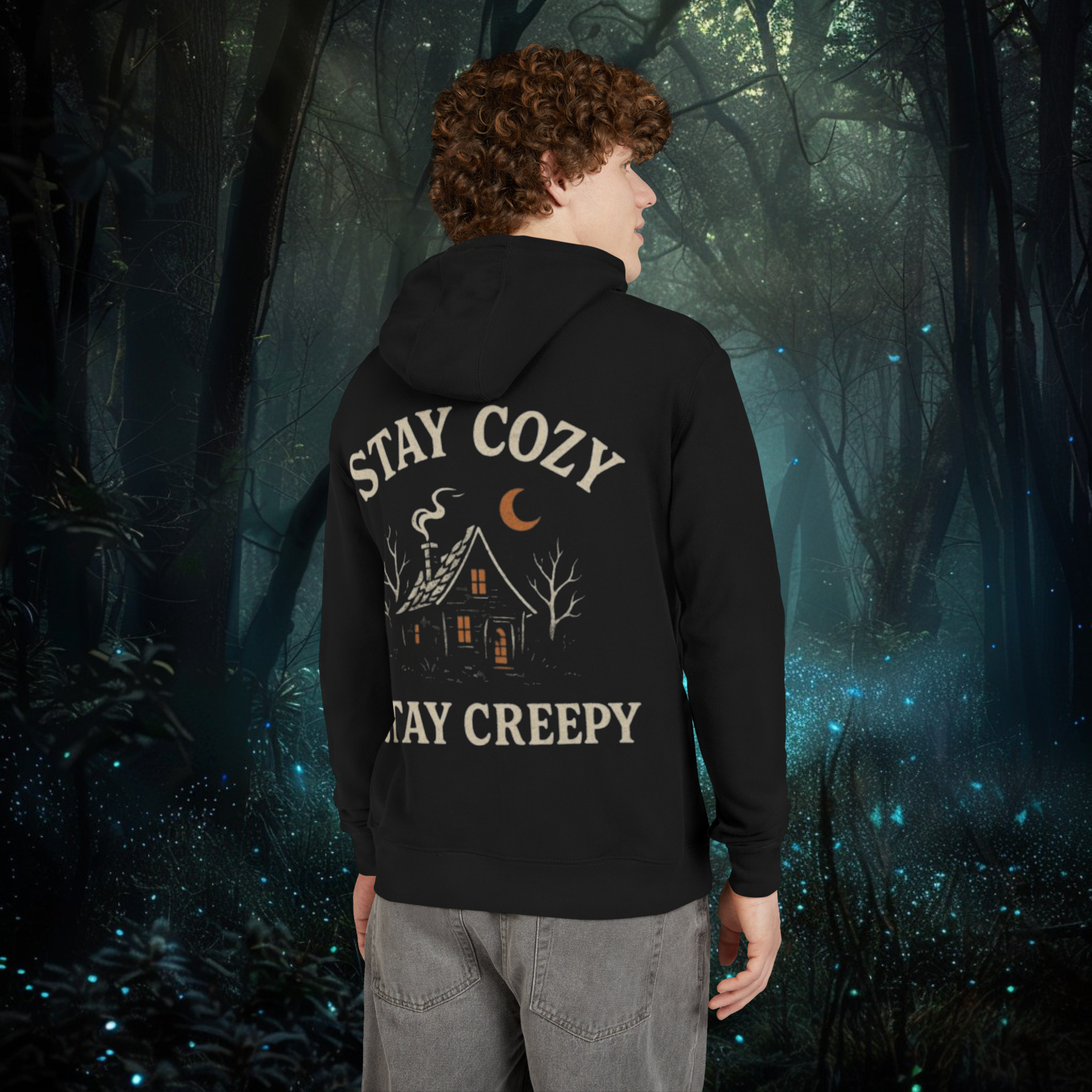 Person wearing a black hoodie with 'Stay Cozy, Stay Creepy' text in a forest setting